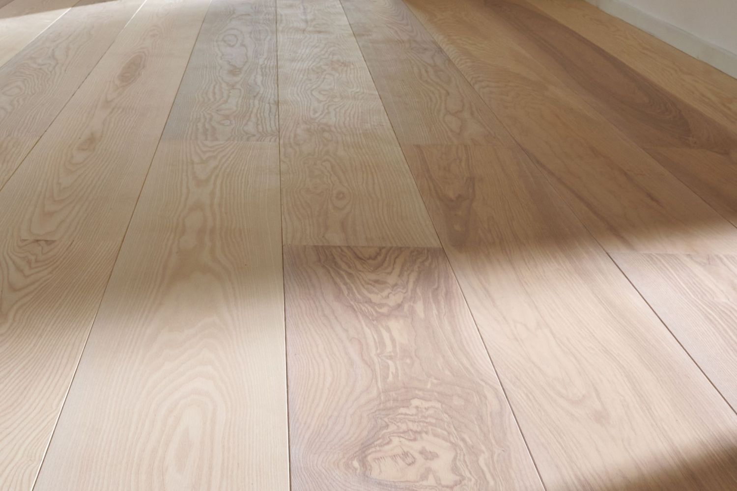Nahaufnahme eines Esche Holzbodens mit sichtbarer Maserung und Schattenverlauf