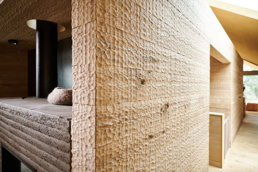 Nahaufnahme einer Eiche Wandpaneele mit grob behauener Holzoberflaeche in einem modernen Innenraum mit sichtbaren Fenstern und Holzboden