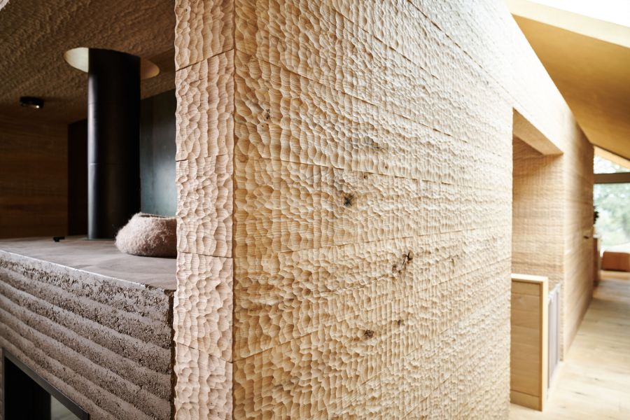 Nahaufnahme einer Eiche Wandpaneele mit grob behauener Holzoberflaeche in einem modernen Innenraum mit sichtbaren Fenstern und Holzboden