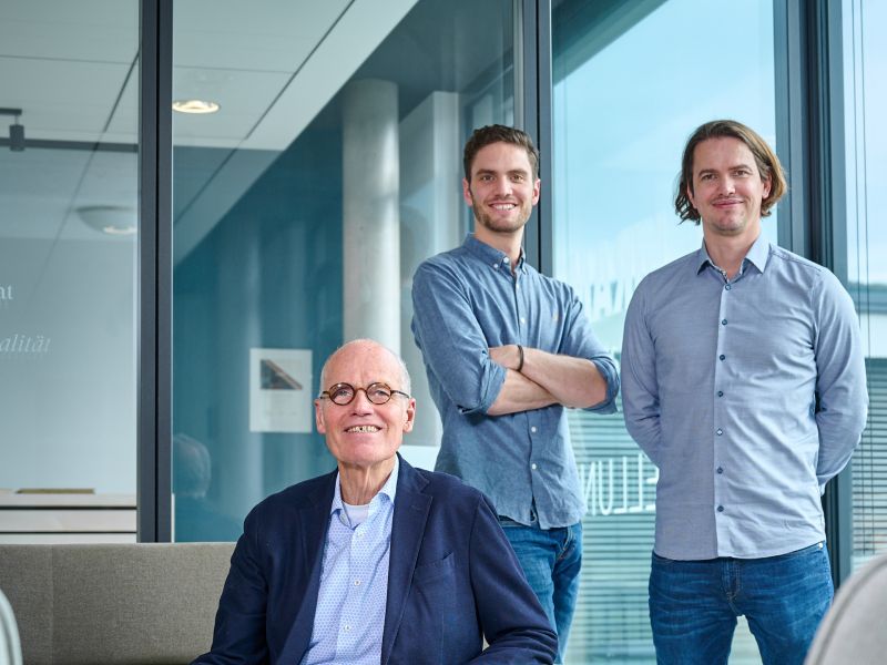 von Saucken family in a modern office, one sitting in an armchair, two standing behind in front of large windows.