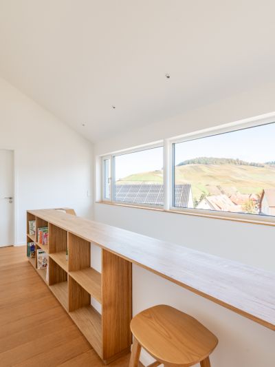 Blick in einen Flur im Obergeschoss. Rechts ist der Handlauf der Treppe, der in einen Einbauschrank aus Eiche übergeht zu sehen.