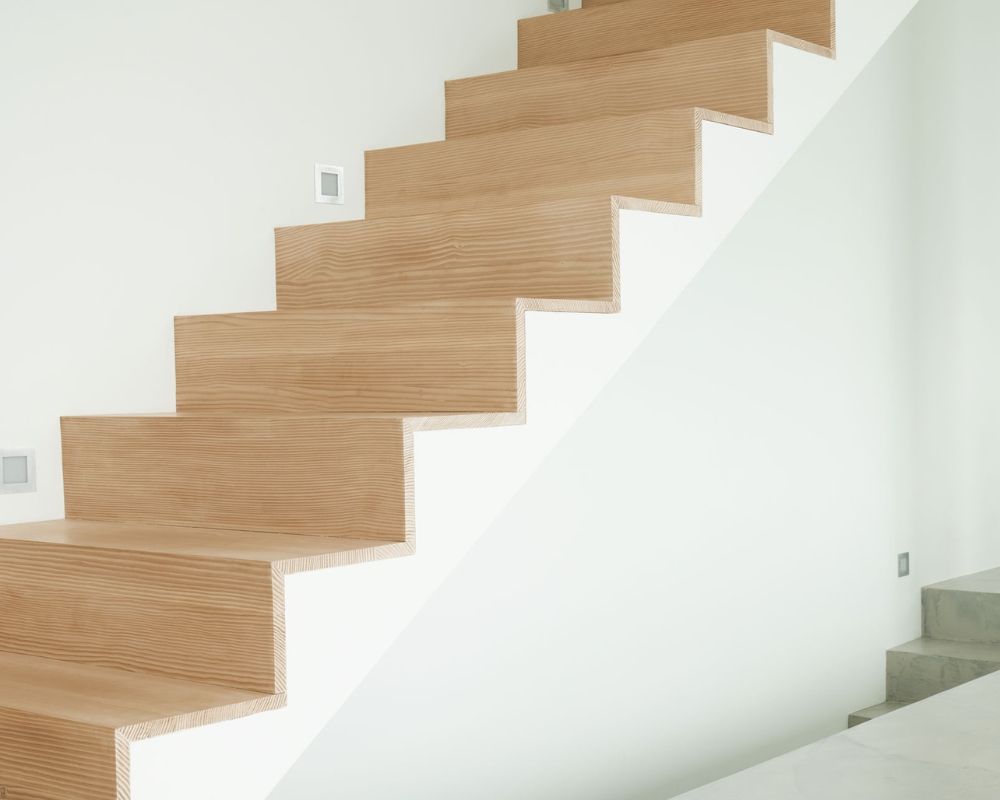 Escalier en bois de douglas avec marches droites et nettes; contre un mur blanc dans un intérieur moderne