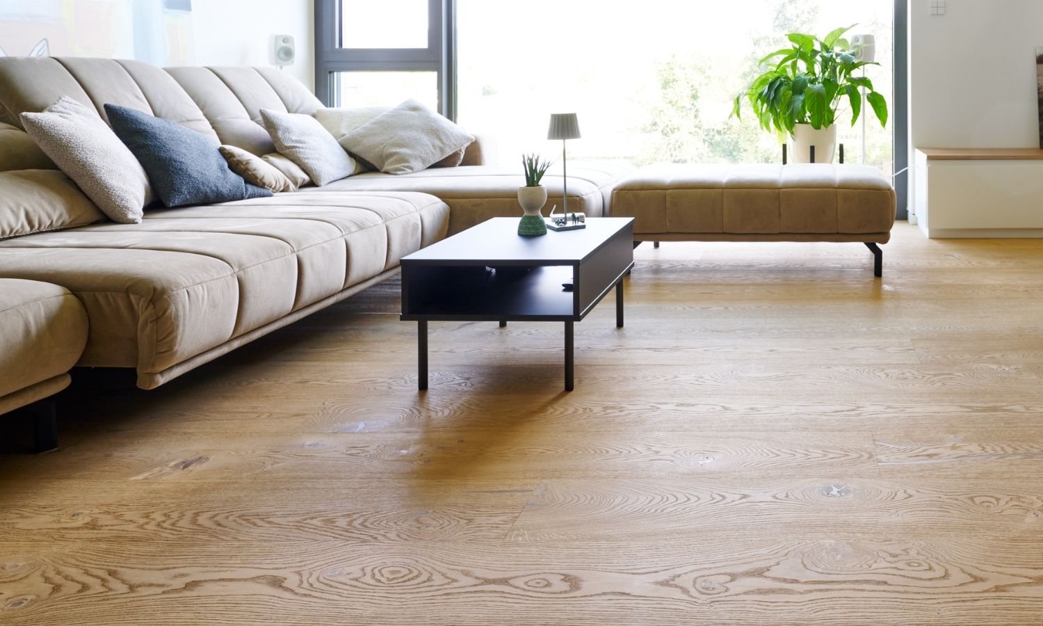 Modern rectangular fireplace with glass front and firewood on oak floorboards, two round stools in the background.