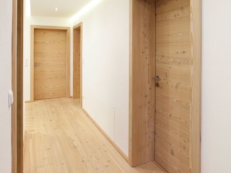 Couloir avec parquet en meleze clair de classement avec noeuds, murs blancs et eclairage de plafond moderne.