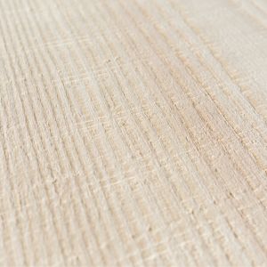 Nahaufnahme eines Weißtanne Dielenbodens mit sägerauer Optik. Auf dem Holz verlaufen die Spuren der Bandsäge als Striche horizontal und vertikal zueinander. So ist ein kariertes Oberflächenmuster zu sehen.