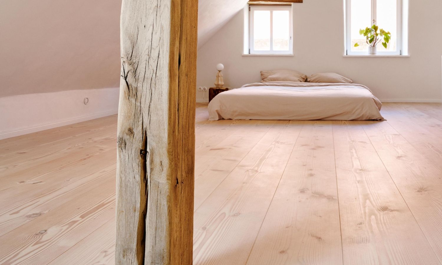 Bedroom with wooden beams; Douglas fir wooden floor; a bed in front of two windows; plants on the windowsill